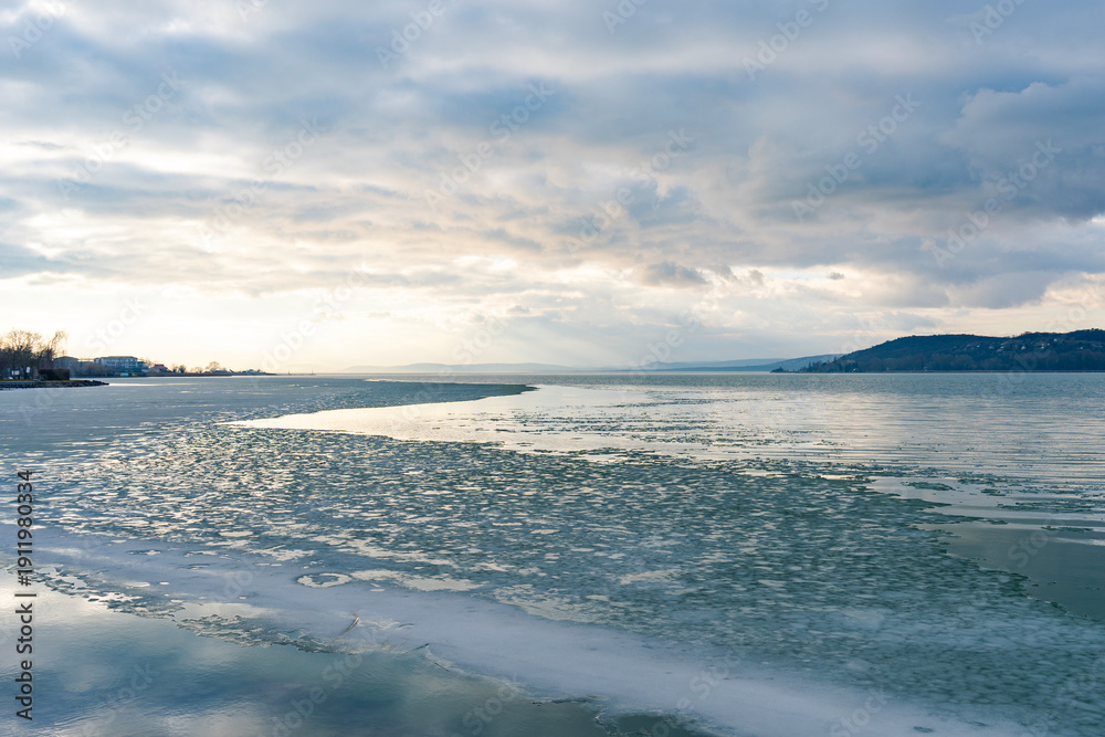 Fototapeta premium Frozen lake with dramatic cloudy winter sky on Lake Balaton in Hungary