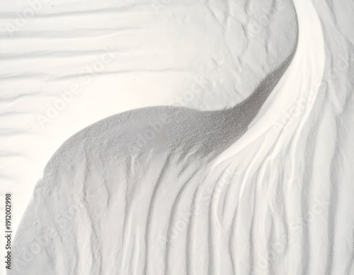 Aerial shot of white sand dunes, with shadows, creating an abstract, textured landscape