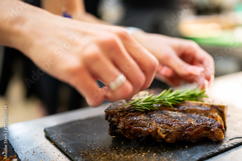 Fotografi A chef meticulously places a fresh rosemary sprig onto a perfectly seared, juicy
