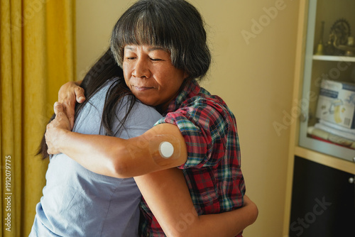 Foto Happy asian mother with diabetes patch hugging daughter at home - Family love, l