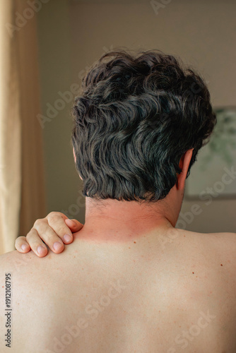 Tableau sur toile Rear view of a man with dark curly hair, sunburn on the back of his neck, left h