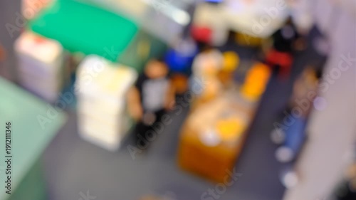 A blurry image of a crowded room with people standing around. Scene is busy and chaotic