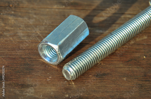 Fényképezés Long coupling nut and threaded bolt on a rustic wooden background