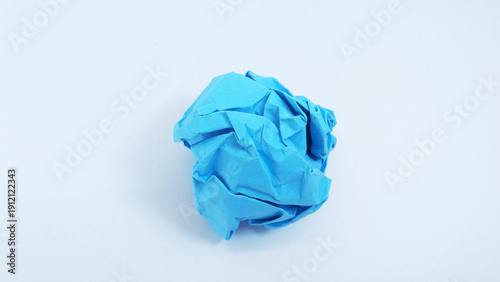 Close up of a vibrant blue crumpled paper ball, symbolizing a discarded idea, mistake, or creative block, isolated on a clean white background. Concept of brainstorming, frustration, and recycling.