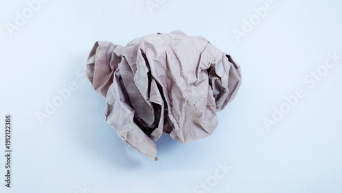 Close up of a vibrant beige crumpled paper ball, symbolizing a discarded idea, mistake, or creative block, isolated on a clean white background. Concept of brainstorming, frustration, and recycling.
