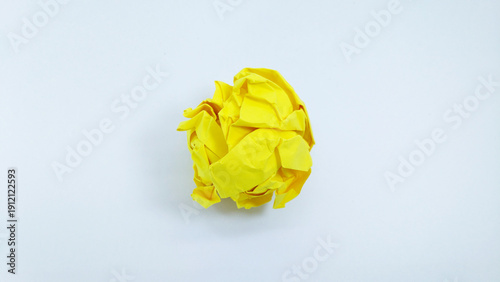 Close up of a vibrant yellow crumpled paper ball, symbolizing a discarded idea, mistake, or creative block, isolated on a clean white background. Concept of brainstorming, frustration, and recycling.