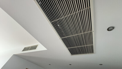 From bottom view of air conditioning wall mounted ventilation system on ceiling in white clean hotel guest room background. Hotel room air ventilation grill on the wall.