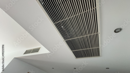 Quadro su tela From bottom view of air conditioning wall mounted ventilation system on ceiling in white clean hotel guest room background