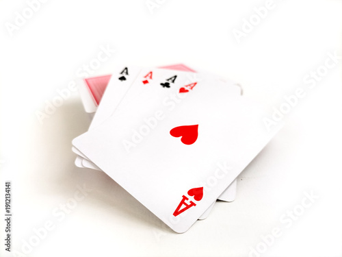Four playing cards displaying the aces of hearts, clubs, spades, and diamonds are shown, fanned out on a white background.