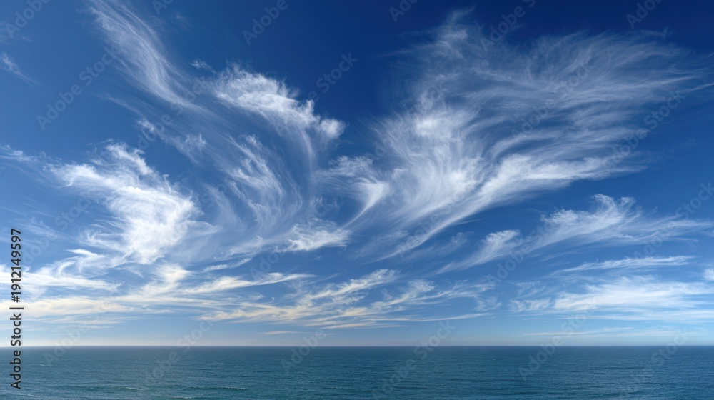 Obraz premium Azure Tapestry: High-altitude cirrus clouds paint an ethereal picture against a vast expanse of blue, above the calm sea, an awe-inspiring symphony of nature's beauty and wonder.