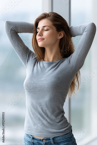 Woman standing by a window with eyes closed enjoying the moment during daytime in a bright indoor space