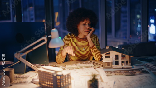 Overworked designer planning house exterior sitting night workplace. Tired woman