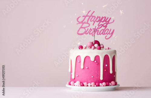 Pink celebration birthday cake with happy birthday banner and drip icing
