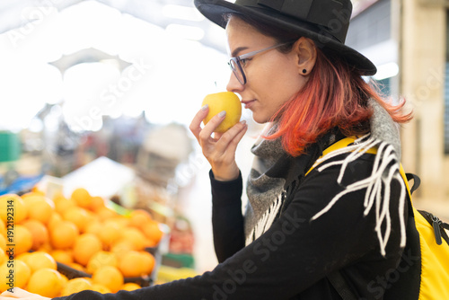 Young woman smelling fresh yellow apple at market