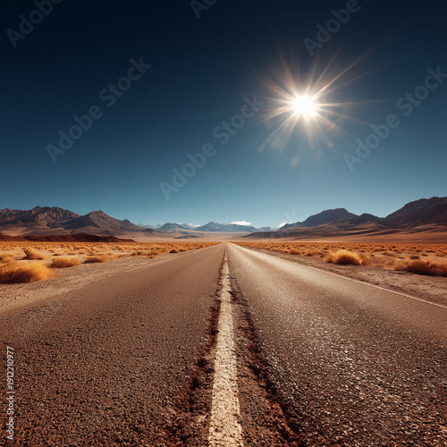 Long straight highway through arid landscape with mountains and clear blue sky.