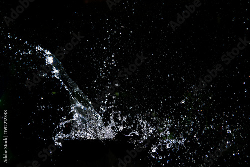 Splashing water with a dark backdrop, creating a dynamic and refreshing effect. The droplets scatter in various directions