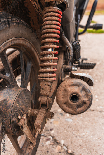 Detailed plan of parts of a black, dirty, muddy, and rusty motorcycle that is in need of maintenance.