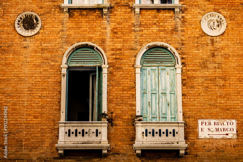 detail of windows with open green shutters on a historic house in Venice - one window is closed and the other is open