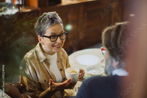 Tablou pe pânză Senior woman smiling and talking during coffee date