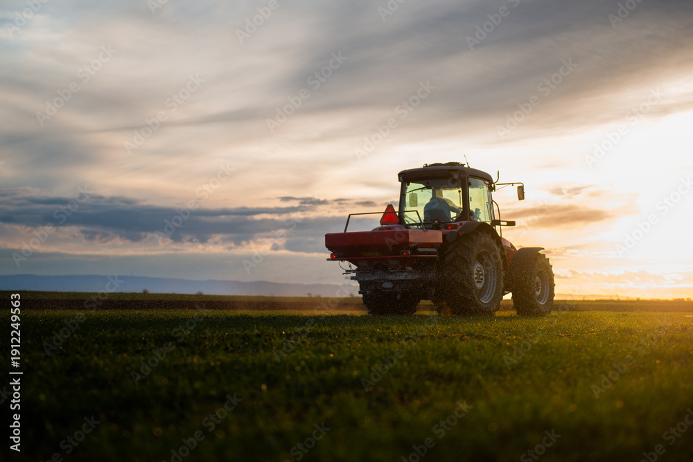 Fototapeta premium Tractor spreading artificial fertilizers in field