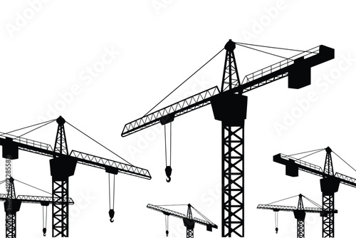 Multiple black silhouette tower cranes stand against a bright white background for.