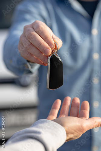 car service. Man hands over car keys to another person in a service setting. Vertical