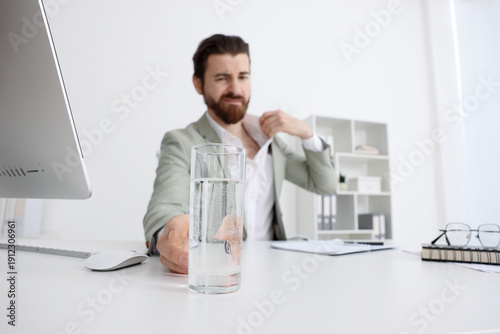 Φωτογραφία Man with glass of water suffering from heat at table near white wall indoors, se