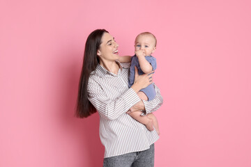 Happy mother with her cute baby on pink background