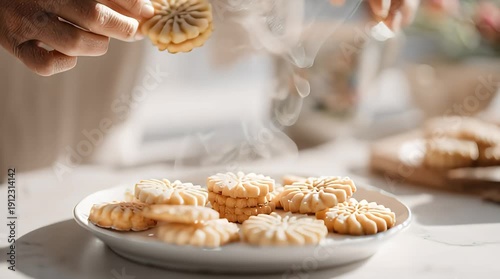 Person arranging freshly baked cookies on a plate in bright kitchen
