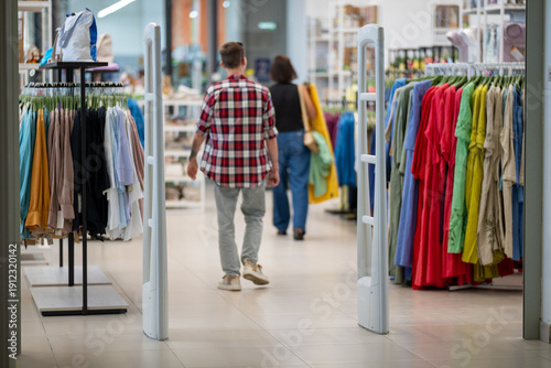 Customers walking through a clothing store entrance between security gates