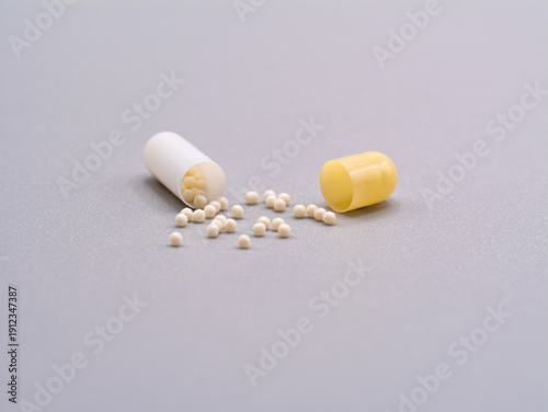 Fotografie Open Capsule with White Pellets on Grey Background
