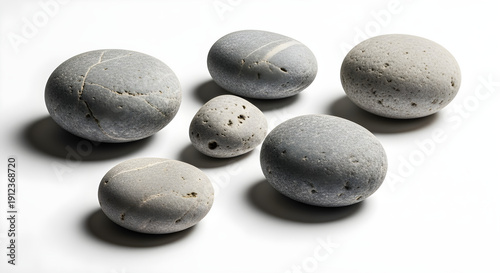 A harmonious arrangement of smooth, gray natural pebbles with subtle textures, casting soft shadows on a pristine white background, symbolizing tranquility and grounded serenity