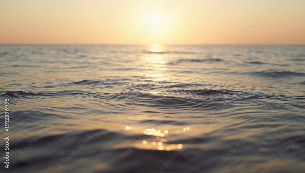 Fototapeta premium Golden ocean surface at sunset with gentle waves and warm light