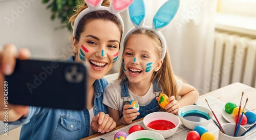 Happy Mother and Daughter with Face Paint Taking Selfie While Decorating Easter Eggs