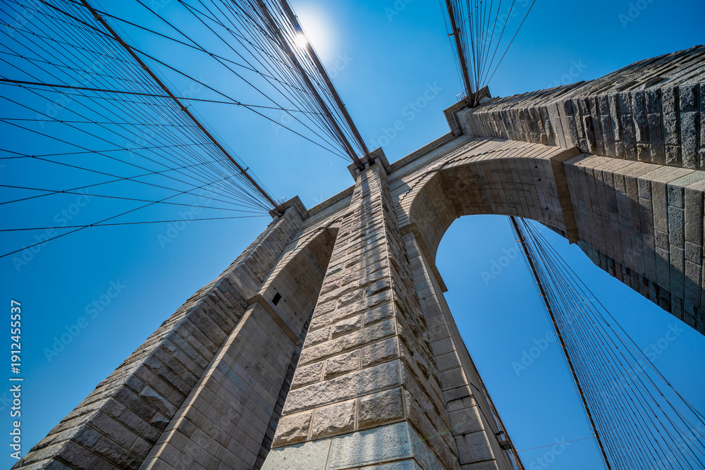 Fototapeta premium Brooklyn Bridge walkway perspective with cables and urban cityscape of NYC