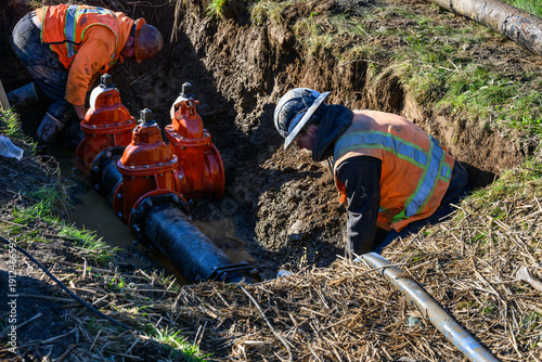 Fotografie Workman installing a wedge gate valve in municipal water supply distribution pip