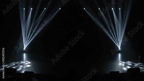 Dark Concert Stage with Bright White Spotlight Beams Illuminating Empty Performance Space for a Dramatic Night Show.