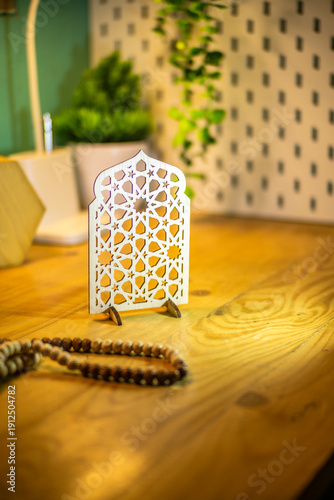 Elegant wooden Islamic geometric star pattern ornament on a wooden desk, blurred background with plant, perfect for Ramadan and Eid decoration