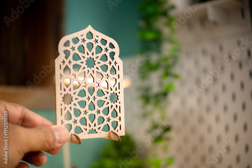 Elegant wooden Islamic geometric star pattern ornament on a wooden desk, blurred background with plant, perfect for Ramadan and Eid decoration