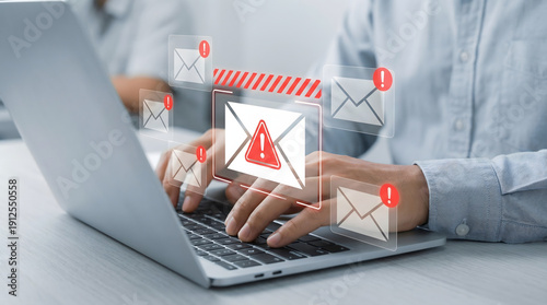 Person typing on laptop with spam email warning icons