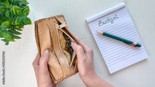 An open leather wallet with coins inside on a light background. Next to it is a notebook with the word 