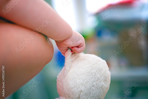 Wallpaper Mural Child's hand, supported by mother, holding a soft cat toy by the ear. Tender parenting and play moment. Torontodigital.ca