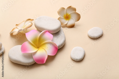 Beautiful plumeria flowers with stones on beige background