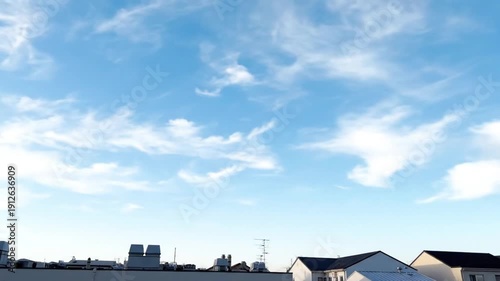 Serene blue sky with wispy clouds over suburban rooftops
