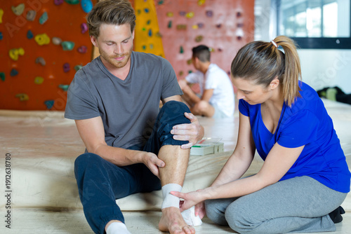 Bild auf Leinwand female trainer wrapping bandage to injured ankle