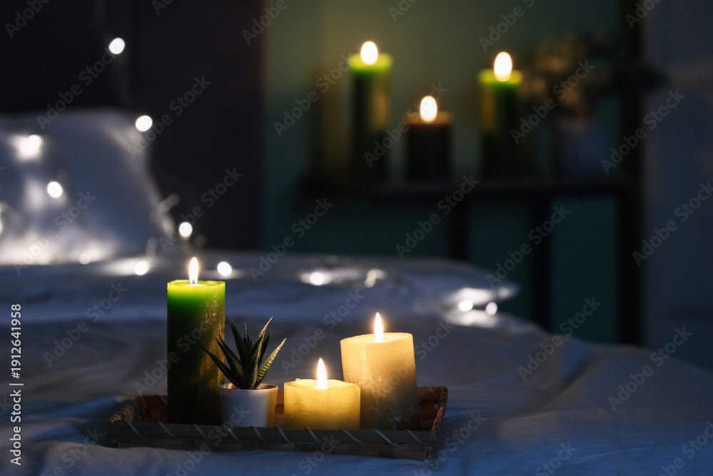 Φωτογραφία Cozy bedroom interior with burning candles on tray, soft fairy lights and blurre