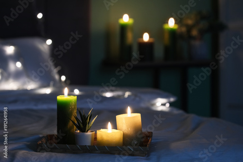 Φωτογραφία Cozy bedroom interior with burning candles on tray, soft fairy lights and blurre