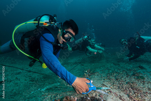 Foto Divers remove ghost net from coral reefs to protect marine life and restore habi