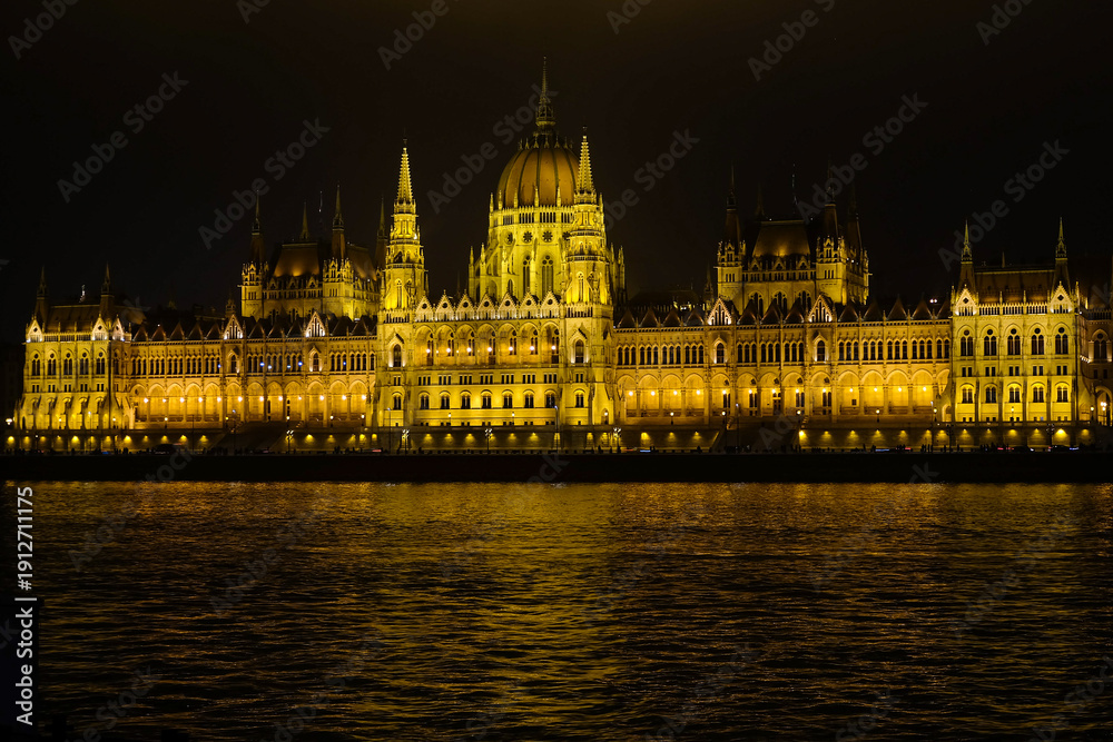 Fototapeta premium The Hungarian Parliament Building at night with lights and illumination, panorama view over the Danube river on a chilling winter day
