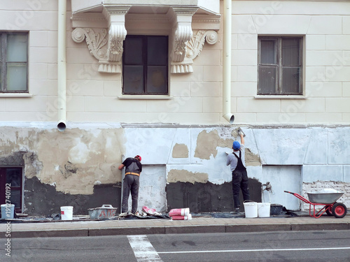 Bild auf Leinwand Worker plastering building, plastering job underway on building facade